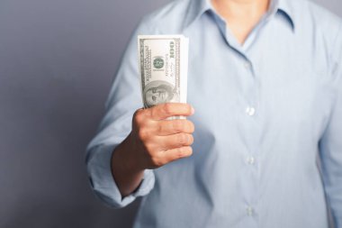 İş ve finans kavramı. Stüdyoda gri arka planda dururken bir Amerikan dolarının el ele tutuşması. Yakın plan fotoğraf. Metin için boşluk.