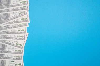 Yüz Amerikan doları banknotları mavi arka planda izole edilmiş ve metin için fotokopi alanı var. İş ve finans kavramı.
