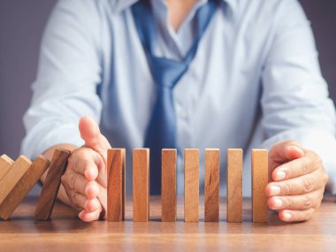 Risk yönetimi konsepti. İş dünyası çökmeden önce domino işi krizini durduran iş adamlarının yakın çekimi. İş krizi yönetimi kavramsal.