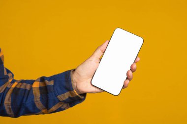 Teknoloji, iletişim ve reklam kavramı. Sarı arkaplan ile ayakta dururken mesaj veya bilgi için boş bir kopya alanı ekranı olan cep telefonunun yakın plan görüntüsü