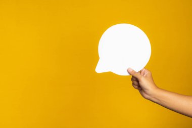 Konuşma balonu konsepti. Sarı zemin üzerinde boş bir konuşma balonunun el ele tutuşması ve metin için kopyalama alanı. Yakın plan fotoğraf.