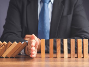 İş risk yönetimi konsepti. İş dünyası çökmeden önce domino işi krizini durduran bir iş adamının eli. Yakın plan fotoğraf.
