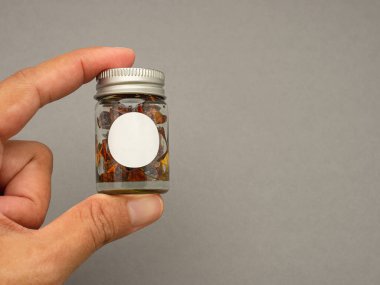 Gri arka planda bir şişe bitkisinin el ele tutuşması. Marka modeli için boş etiket. Bitki ürünleri ve sağlık ürünleri konsepti. Üst Manzara. Yakın plan fotoğraf.
