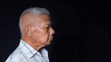 Stüdyoda siyah bir arka planda dikilirken başka tarafa bakan son sınıf bir adamın yan görüntüsü. Mesaj için yer var. Yaşlılar ve sağlık konsepti