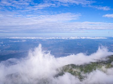 Scenic view of the mountains against fog, clouds, and a blue sky. clipart