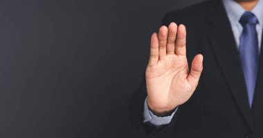 Takım elbiseli bir işadamı stüdyoda gri arka planda dikilirken elleriyle jestleri durduruyor. Uzayı kopyala Yakın plan fotoğraf. İş ve strateji kavramı.