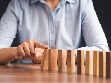 İş konseptinde risk ve strateji. Yakın plan. Tahta bir bloğu domino taşına bastır.