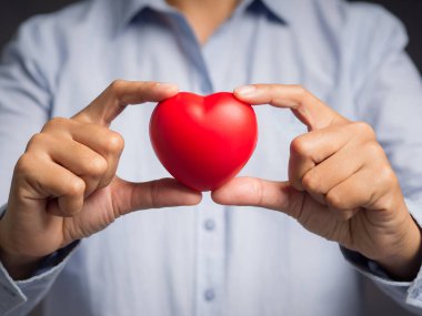Kırmızı kalp şeklini tutarken yakın plan. Midseksiyon. Yakın plan fotoğraf. Mesaj için yer var. Cesaret, sevgi ve bağış kavramı