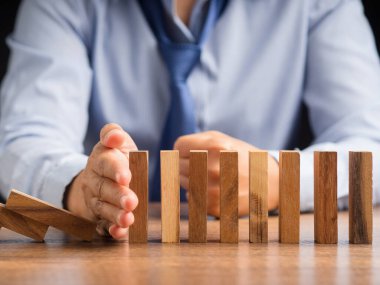 Risk yönetimi konsepti. İş dünyası çökmeden önce domino işi krizini durduran iş adamlarının yakın çekimi. İş krizi yönetimi kavramsal