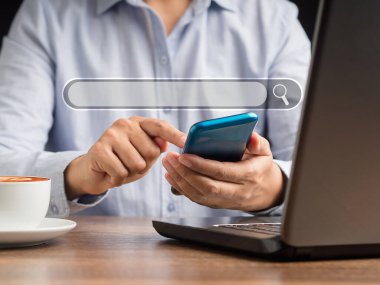 Yakın çekimde, ofiste otururken ilgilendikleri şeyi bulmak için akıllı telefon kullanıyorlar. İnternet ağı konsepti hakkında bilgi aranıyor. Veri arama teknolojisi kavramı