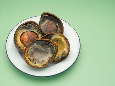 Çürümüş avokadolar yeşil arka planda beyaz bir tabakta ikiye bölünmüş. Mesaj için yer var. Üst görünüm