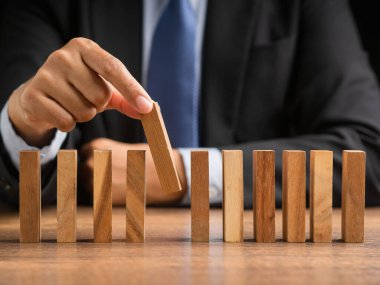İş planlaması, risk ve kriz yönetimi konsepti. Takım elbiseli bir işadamı, masanın üzerindeki tahta bloklardan birini seçiyor.