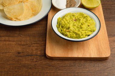 Tahta kesme tahtasındaki bir kasede taze guacamole. Sağlıklı avokado yayılımı. Düz yatıyordu. Geleneksel Meksika hazırlığı kavramı