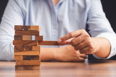 İş büyümesi ve başarı konsepti için yönetim ve strateji planları riski. Çalışma masasında otururken tahta blok oyunu oynayan işadamının eli. Metin için boşluk