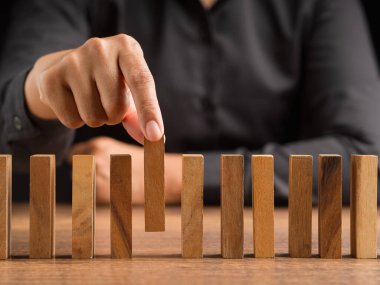 İş planlaması, risk ve kriz yönetimi konsepti. Siyah tişörtlü bir işadamı, masanın üzerindeki tahta bloklardan birini seçiyor.