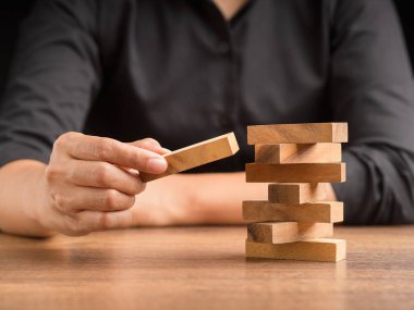 İş büyümesi ve başarı konsepti için yönetim ve strateji planları riski. Çalışma masasında otururken tahta blok oyunu oynayan işadamının eli. Metin için boşluk