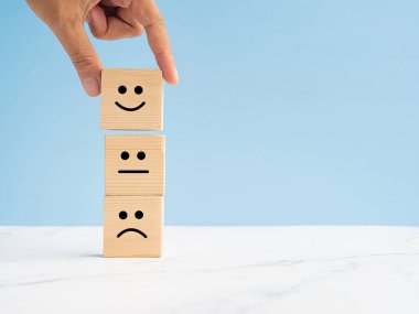 İnsanlar servisimizi tatmin etmek için tahta küpün üzerindeki gülen surat ikonuyla geri bildirim yapıyorlar. Müşteri geribildirimi, hizmet değerlendirmesi, deneyim ve tatmin kavramı. Metin için boşluk