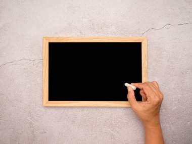 Elinde tebeşirle küçük bir tahtaya bir şeyler yazmak üzere. Eğitim ve okul konseptine geri dönüş. Metin için boşluk