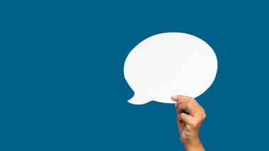 Konuşma balonu konsepti. Mavi arka planda boş bir beyaz konuşma balonunun el ele tutuşması. Mesaj için yer var. Yakın plan fotoğraf..