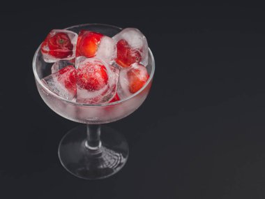 Buzlu taze kirazlı şarap bardağı. Soğuk içecek ferahlatıcı. Yaz partisi. Masadaki olgun kırmızı acerola kirazı ve yeşil yapraklar. Yüksek C vitamini meyveleri