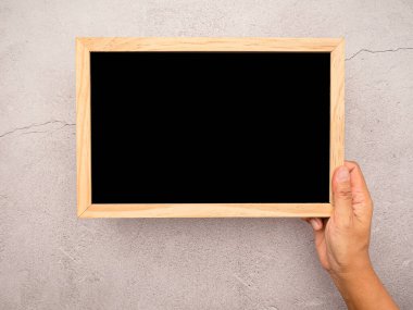 Beton zeminin üzerinde ahşap bir kenarı olan küçük boş bir tahtanın el ele tutuşması. Mesaj için yer var. Üst görünüm