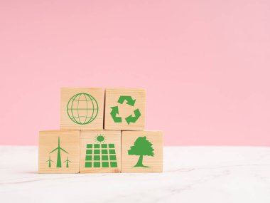 World Earth day concept. Save earth and environment, net-zero emissions, and carbon neutral. Wooden cubes with eco-friendly icons over a marble floor against a light pink background clipart