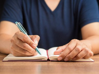 Ofiste otururken, ahşap bir masanın üzerine bir kalem yazarken yakın plan. Mesaj için yer var. İş ve strateji planlama kavramı