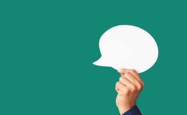 Stüdyonun yeşil arka planında beyaz bir konuşma balonunu tutan yakın plan. Yakın plan fotoğraf. Metin için boşluk