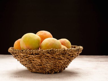 Siyah arka planda sepetin içinde bir grup taze şeftali meyvesi. Yan görüş. Yakın plan fotoğraf. Sağlıklı gıda ve meyve kavramı