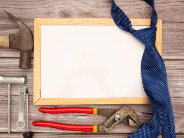 Babalar Günün kutlu olsun. Boş bir mini tahta, kravat, inşaat aletleri, çekiç, tornavida, vida ve pense tahta bir masada. Üst Manzara. Metin için boşluk