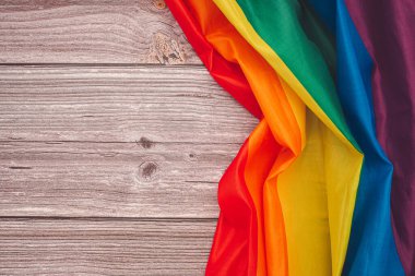 Gökkuşağı bayrağının üst görüntüsü veya metin için kopyalama alanı olan ahşap bir masanın üzerindeki LGBT. Düz yatıyordu