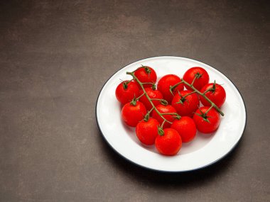 Kırmızı olgun taze vişneli domatesler ve yeşil saplı domatesler bağbozumu arka planında beyaz bir tabakta. Üst Manzara. Mesaj için yer var. Yakın plan fotoğraf.