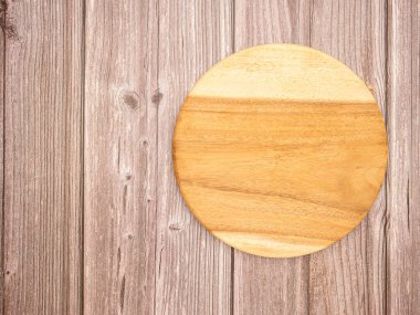 Tahta bir masanın üzerindeki boş tahta kesme tahtasının üst görüntüsü. Metin için boşluk