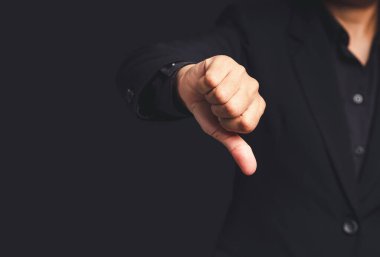 Olumsuz görüş. Gri bir arka planda dururken siyah takım elbiseli bir işadamının baş parmağını kaldırdığı yakın plan. Müşteri hizmetleri ve memnuniyet araştırmaları konsepti