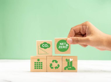 2050 'de ağ-sıfır emisyonları. Dünya Günü konsepti. Dünyayı, çevreyi ve karbonu koru. Ahşap bir masanın üzerinde çevre dostu simgelerle ahşap bir küp tutuyor.