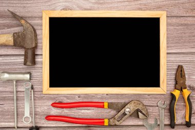 Boş bir karatahta ve inşaat aletleri, çekiç, tornavida, vida ve pense. Üst Manzara. Metin için boşluk