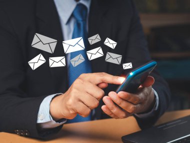 Akıllı telefon tutan bir işadamı ofiste otururken e-posta simgeleriyle yeni bir mesaj alır. Cep telefonundan e-posta bildirimi. E-posta pazarlama konsepti. Yakın plan fotoğraf.