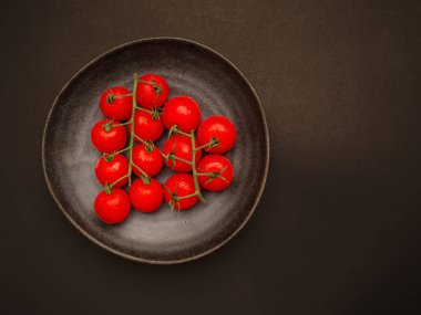 Kırmızı olgun domatesler seramik bir kapta, eski arkaplanda. Üst Manzara. Mesaj için yer var. Yakın plan fotoğraf.