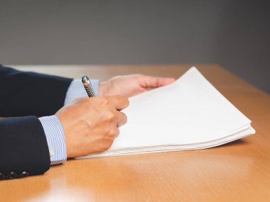 Ofiste çalışırken evrakları imzalayan bir işadamının yakın çekimi. Şirket yöneticisi, işletme sahibi, işveren kontrat imzalayan, anlaşma imzalayan, iş yerindeki kağıt raporu