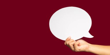 Konuşma balonu konsepti. Kırmızı arkaplan üzerinde boş bir beyaz konuşma balonu sembolü tutan yakın plan. Metin için boşluk