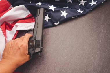 Amerikan bayrağının bir parçası ve klasik arka planda silah tutan bir el.