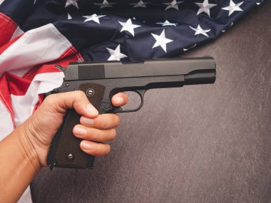 Amerikan bayrağının bir parçası ve klasik arka planda tabanca tutan bir el. Mesaj için yer var. Üst görünüm