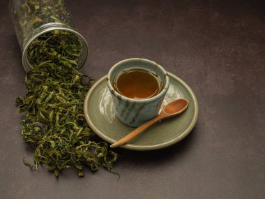 Kutunun dışında kuru kenevir yaprağı çayı ve esrarlı çay fincanı. Dokulu marihuana yaprakları. Kenevir otlu içecek kavramı