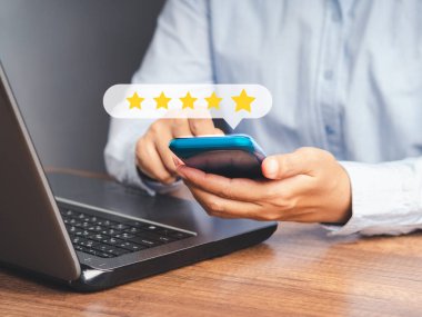 Akıllı telefon kullanan bir müşteri, beş yıldızlı ikona ofiste otururken verdiği hizmet için çok etkilenmiş bir not veriyor. Mesaj için yer var. Müşteri hizmetleri ve memnuniyet araştırmaları konsepti