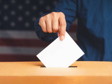 Seçimlerde oy pusulasına Amerikan bayrağı geçmişi olan bir oy pusulası koyan elle seçmen. Özgürlük demokrasi kavramı. Yakın plan fotoğraf.