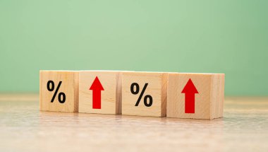 Finans ve faiz oranları kavramı. Tahta küplerde kırmızı oklar ve yeşil arka planlı ahşap bir masada yüzde yüz semboller. Yan görünüm