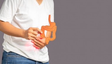 Kolon sembolü tutan ellerin yakın çekimi ve karın ağrısına dokunmak. Gri arka planda dururken karın ağrısı.