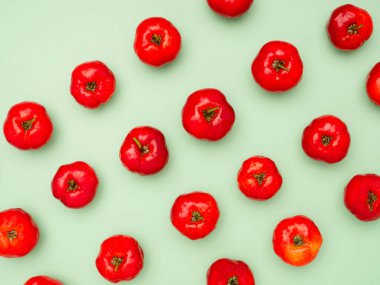 Açık yeşil zemin üzerinde izole edilmiş olgun kırmızı acerola kirazlarının üst görüntüsü. Yüksek C vitamini ve antioksidan meyveler. Mesaj için yer var. Yakın plan fotoğraf. Sağlıklı meyve kavramı