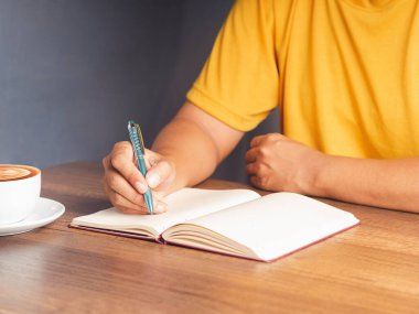 Yakın plan, masanın üzerindeki bir deftere kalem yazarken. Mesaj için yer var. Rapor alma veya yazma kavramı