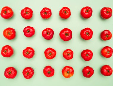 Açık yeşil zemin üzerinde izole edilmiş olgun kırmızı acerola kirazlarının üst görüntüsü. Yüksek C vitamini ve antioksidan meyveler. Mesaj için yer var. Yakın plan fotoğraf. Sağlıklı meyve kavramı